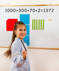 Girl using 131-Piece Jumbo Magnetic Base Ten Blocks Set for Math Place Value on a whiteboard in K-3 classroom.