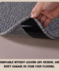 Hand lifting corner of rug to show 16 Pack Anti Slip Rug Tape Double Sided Carpet Grip For Hardwood Floors And Tiles Prevents Slipping Curling And Bunching On Area Rugs No Slip Pad That Stays Put.