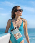 Woman at beach with 5 Pack Clear Waterproof Dry Bags For Camera, Phone, Maps And More With Lanyard, wearing aqua swimsuit.