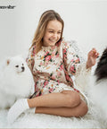 Person in floral dress sitting with two fluffy dogs on a white background