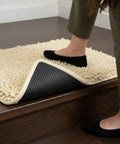 Foot stepping on rug with Heavy Duty Rug Gripper Pads With Adhesive Strips For Non Slip Carpet Corners Kit in use on stairs