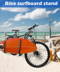 Adjustable Bicycle Surfboard Rack With Upgraded Design For Shortboards Longboards SUPs Paddles Windsurfing Boards And Skis Universal Bike Carrier Constructed From Aluminum And Stainless Steel Rotatable Angles For Easy Mounting And Smoother Rides attached to bicycle on beach with surfboard