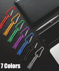 25 Pack Mini Keychain LED Flashlights With Carabiner For Outdoor Summer Use, shown in 7 colors with a pen and phone nearby.
