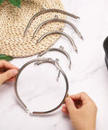 Metal Purse Frame Set Six Pcs With Vintage Arch Kiss Lock Clasp Embossed Silver Tone shown with hands for purse making.