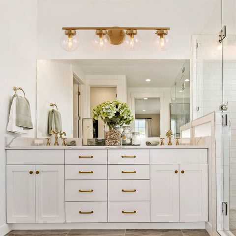 Gold Bathroom Vanity Light 28 Inch Four Light Fixture With Clear Glass Globes, Hand Painted Gold Finish in bright bathroom space