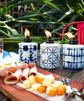 Tie Dye Glass Tabletop Torches 3 Pack For Outdoor Patio, Backyard And Garden Lighting, displayed on a table with snacks