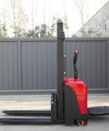 Battery Powered Electric Pallet Stacker Truck With Walk Behind Hydraulic Lift, side view showing red body and black forks.