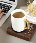 Game Changing Desk Essential Smart Electric Coffee Heated Coaster With Precise Thermostatic Heat Control Adjustable From Forty To Seventy Five Degrees fast warming mug pad with coffee cup on wooden base next to a laptop.