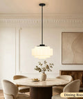 puncoll Vintage Black Milk Glass Pendant Light, 15.7'' White Chandelier hanging above a modern dining table in a bright room.
