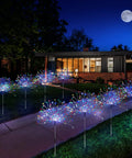 Four Pack Solar Garden Lights With 120 LED Copper Wire Waterproof Fireworks Design Flexible Stakes For Pathway And Lawn Remote Included 8 Modes Colorful Glow For Outdoor Backyard Ambiance illuminating a pathway.