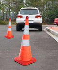 4 Pack 27.6 Inch Collapsible Traffic Cones With Nighttime LED Lights used beside parked cars on a roadside