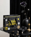Black Birthday Gift Bag For Men With Foil Stamping And Tissue Paper, 12.5 Inch Medium Gift Bag With Greeting Card on a table.