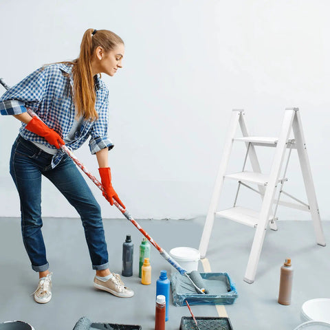 Woman painting with three step aluminum folding ladder with wide anti slip pedals, 330 lb capacity, ultra lightweight portable stepladder.