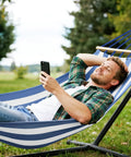 Person relaxing on a Built Tough Portable Camping Hammock With 550Lb Capacity, Thick 320G Canvas, Blue White in a backyard.