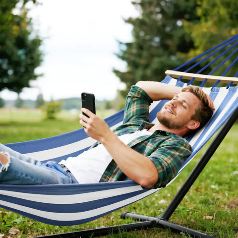Person relaxing on a Built Tough Portable Camping Hammock With 550Lb Capacity, Thick 320G Canvas, Blue White in a backyard.