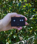 Hand holding AXS1 3-Button Gate Opener Remote Transmitter for Automatic Gates, Authentic OEM, easy pairing, in garden setting.