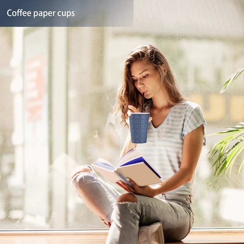 Woman holding a 240 Pack 12 Oz Disposable Paper Cups Navy Floral Hot And Cold Bev Cups For Home Office Restaurant And Events Leak Proof With Rolled Rim And Poly Lined Interior while reading by a window