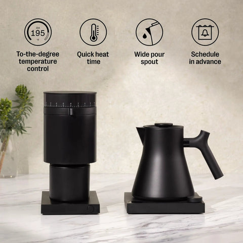 Corvo EKG Pro Electric Tea Kettle With Precise Temperature Control Quick Heat Scheduling And Built In Brew Timer Matte Black With Walnut Handle 0.9 Liter Capacity For Tea Coffee And Cooking displayed next to matching grinder on counter.