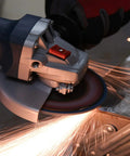 Side view of a grey-blue angle grinder with guard, grinding metal and sparks.