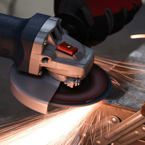 Side view of a grey-blue angle grinder with guard, grinding metal and sparks.