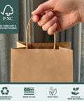 Hand holding Eco Friendly Kraft Gift Bags With Handles Bulk Medium Brown Paper Bags 8x4.25x10.5 Inches Recycled FSC-Certified