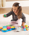 Child playing with Ocean Wonders Build And Spin Gears Toy Set, a colorful STEM construction kit for toddlers, on a carpeted floor.