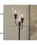 Close-up of Urban Industrial Floor Lamp With Three Glass Shades In Bronze Finish, 60 Inch Tall, lit against a modern wall background.