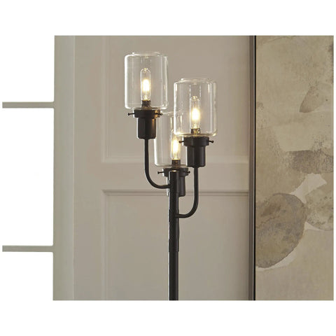 Close-up of Urban Industrial Floor Lamp With Three Glass Shades In Bronze Finish, 60 Inch Tall, lit against a modern wall background.