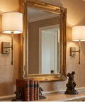 Fabric Shade Wall Sconce Vintage Brass Metal Lamp Bedside Indoor Lighting beside a vintage mirror and books.