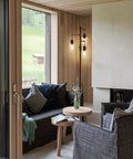 Three Light Industrial Floor Lamp With Glass Shades For Living Room Dope Vibe next to a modern sofa in a cozy living room.