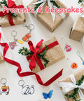 Brown wrapped gift boxes with red ribbons and Shrink Dink keychain kit charms, including animal and butterfly designs.