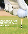 Gloved hand placing golf ball on 150 Pack Bamboo Golf Tees 3.25 Inch Long with black stripe for easy setup on grass
