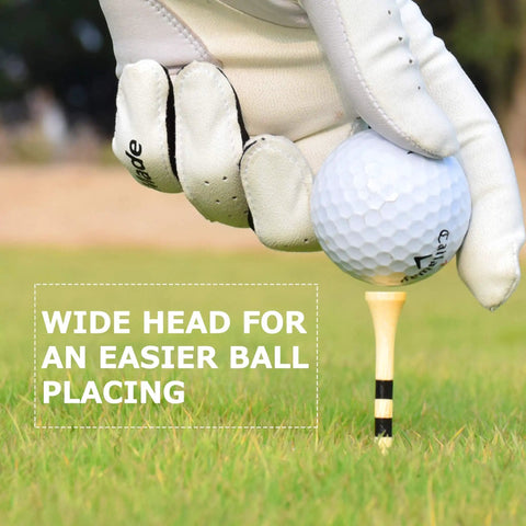 Gloved hand placing golf ball on 150 Pack Bamboo Golf Tees 3.25 Inch Long with black stripe for easy setup on grass