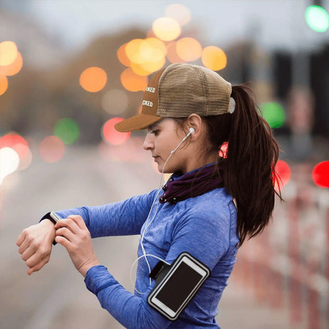 Woman running wearing a brown low profile distressed trucker cap for women, lightweight washed cotton baseball hat, urban backdrop.