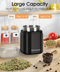 Compact black spice grinder with 200W motor and stainless steel blade shown with herbs and coffee beans on kitchen counter.