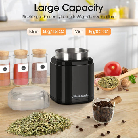 Compact black spice grinder with 200W motor and stainless steel blade shown with herbs and coffee beans on kitchen counter.