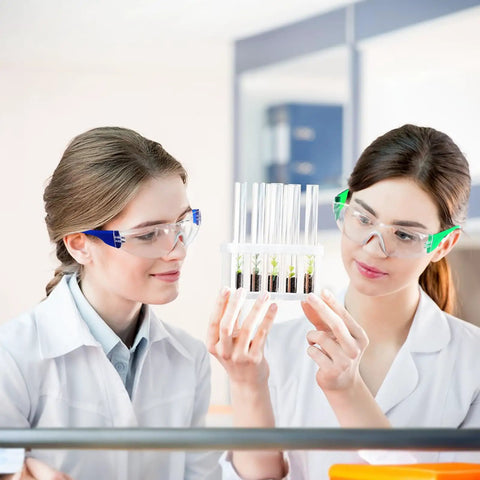 Two women in lab coats wearing 100 Pack Bulk Safety Glasses Featuring Bully Proof Polycarbonate Lenses And Heavy Duty Scratch Protection For Job Sites And Weekend Rigs Rainbow Mix Set.