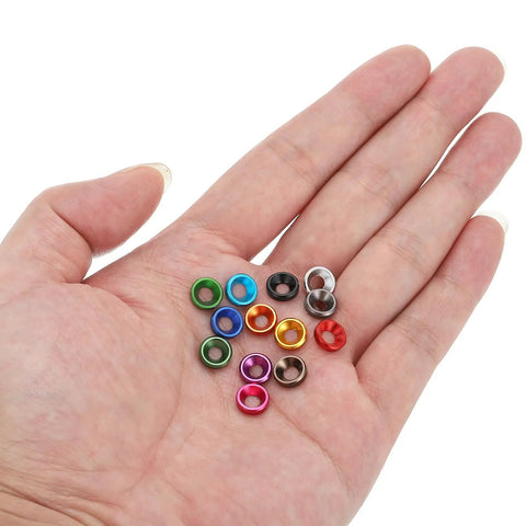 A hand holding a set of multi-colored anodized M3 finishing countersunk washers, 10 pack, for RC FPV drones and PC mechanical accessories.