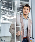 Business professional holding a door, wearing a blazer, in a modern office setting