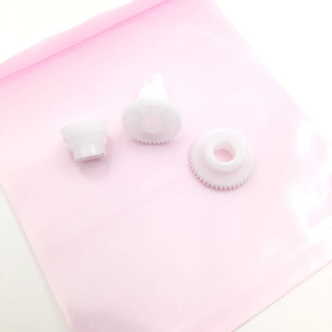 Three white gears from Five Set Change Tractor Idle Gear Kit For OKI Okidata ML320 ML321 ML390 ML391 ML420 ML421 ML490 ML491 ML520 ML521 ML590 ML591 Printers OEM Codes 51215901 51228001 51228101 51238501 on pink background