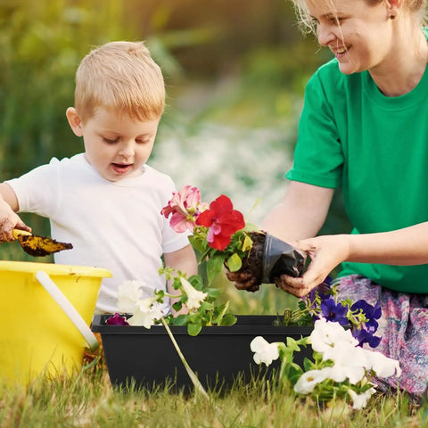 Child planting flowers in Heavy Duty Black Balcony Rail Planters 16.9 Inch Deck Flower Boxes with a parent.