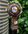 Badass Steampunk Swagger Cane Featuring Skeletal Hand Grasping Evil Eye And Heavy Duty Clockwork Gear Decor Staff For Victorian Costume Fans And Top Tier Home Display Vibes, close-up of skeletal hand and colorful gem.