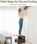 Woman using Rock Solid Bamboo Two Step Stool For Adults And Seniors 400 Pound Heavy Duty Workhorse to reach overhead cabinet.