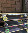 Stack of skateboards against a brick wall with various colored wheels and decks.
