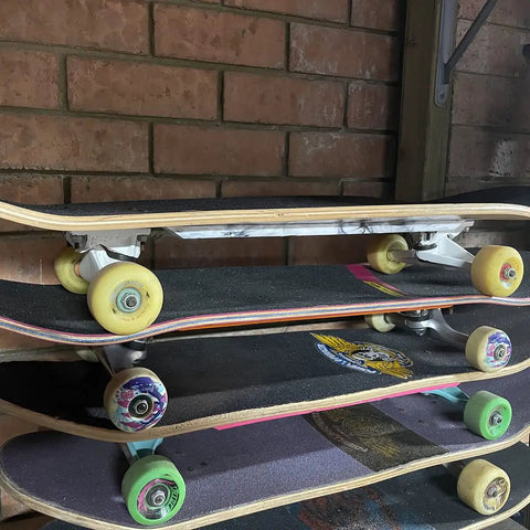 Stack of skateboards against a brick wall with various colored wheels and decks.