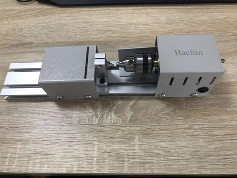 Bachin mini wood lathe side view; silver benchtop lathe with chuck and sliding carriage.