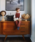 Child sitting on wooden cabinet with typewriter and modern decor.
