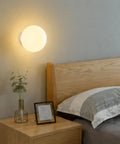 Minimalist Globe Wall Sconce, 1-Light White E27 Round Wall Light Fixture above a bed in a cozy modern bedroom.