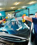 Workers using Heavy Duty Aluminum Suction Cups With Vacuum Handle to install a large glass windshield on a car in a garage