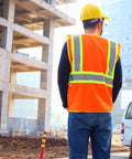 Construction worker wears High Visibility Reflective Safety Vest With Zipper And Pockets In Orange Size M For Men And Women at work site.